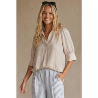 A smiling woman wearing a Naked Zebra - Half Sleeve Hi-lo Bubble Hem Blouse: Wine / L paired with blue and white striped trousers.