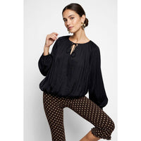 Naked Zebra - Long Sleeve Draped Bubble Hem Blouse in black featuring a round neck with a keyhole tie and a gathered bubble hem, paired with brown polka-dot pants.
