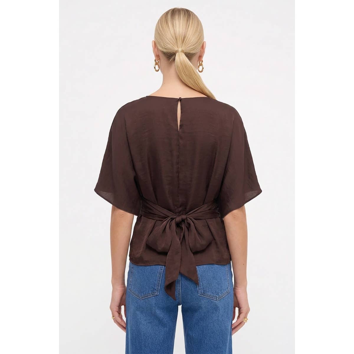 A dark navy Naked Zebra - Back Tie Dolman Sleeve Silky Fall Blouse with a tie-back waist, worn with blue jeans.