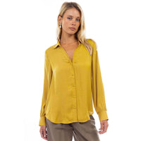 A woman wears a mustard yellow Naked Zebra - Neck Shirt With Open Seam Sleeve: Black / L, featuring a woven polyester button-down design with long sleeves and open seam detailing.