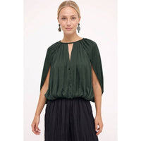 Woman wearing a Naked Zebra - Silky Draped Cape Sleeve Blouse: Wine / L, featuring a dark green, silky draped cape-sleeve design with a keyhole neckline.