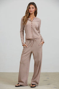 A woman is wearing the Creamon - CTP3592 BROWN Lounge Striped Button Down Top & Pants Set in Brown Stripe, paired with black sandals, standing against a plain light background.