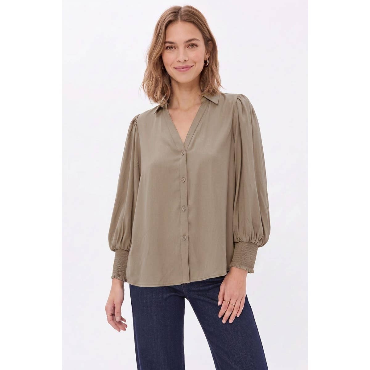 A woman wears a Naked Zebra - Soft Billowy Sleeve Button Front Blouse in wine, featuring a taupe V-neck, button-front design, and billowy sleeves with smocked cuffs.