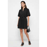 A woman wears a Naked Zebra - Puff Sleeve Cinched Waist Mini Dress: Navy / L, styled with a small black handbag and black slide sandals.