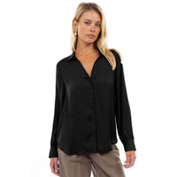 A woman wears a black Naked Zebra - Neck Shirt With Open Seam Sleeve, a woven polyester button-down with long sleeves featuring an open seam detail.