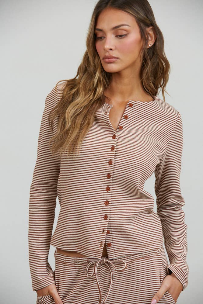 A woman models the Creamon - CTP3592 BROWN Lounge Striped Button Down Top & Pants Set in Brown Stripe (available in S-M-L), featuring a brown and white striped long-sleeve button down top paired with matching wide-leg, drawstring waist pants. She stands against a plain background, one hand in her pocket.