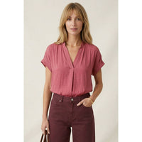 A woman wears a Naked Zebra - Drop Shoulder Regular Blouse: Chocolate / L with a V-neck and dark maroon pants.
